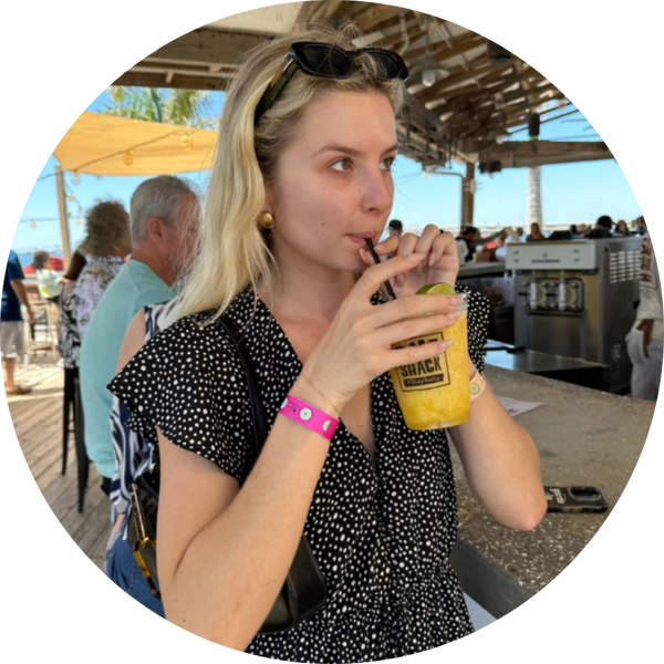 Woman with blonde hair at an outdoor bar holding a drink, wearing the pink Xantus Drinksafe wristband.